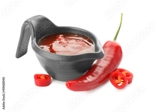 Hot chili sauce in gravy boat and pepper isolated on white