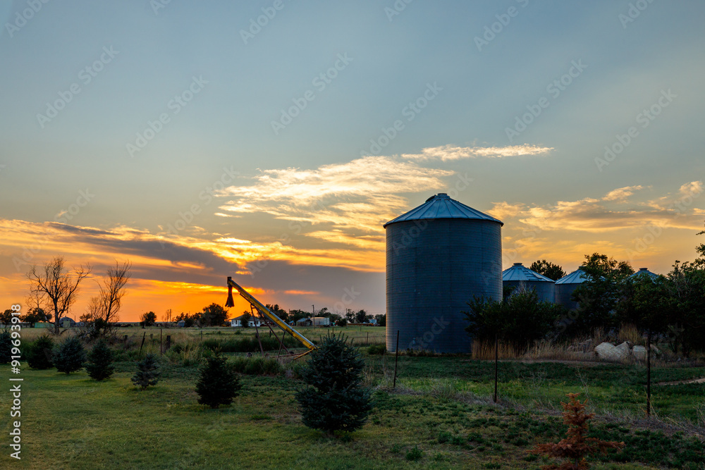 sunset at a farm with silo and equipment visible in the foreground sunset at a farm with silo and equipment visible in the foreground
