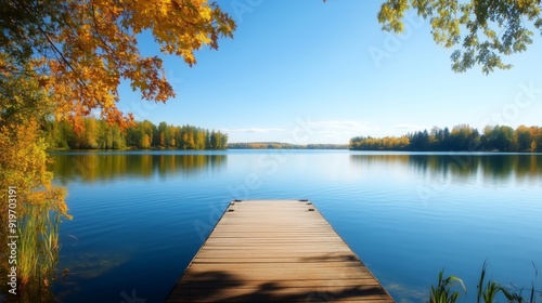 A peaceful lakeside scene with a small dock extending into still waters, framed by trees and a clear blue sky