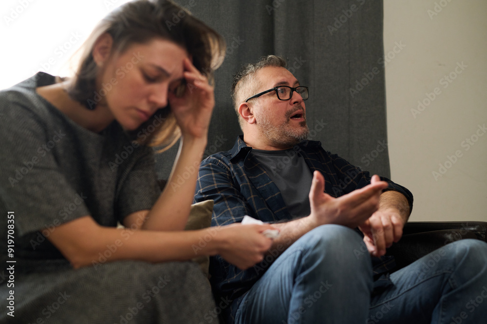 Therapist sitting on chair, discussing concerns with client in an indoor setting Therapist gesturing while client appears stressed and reflective during counseling session Therapist sitting on chair, discussing concerns with client in an indoor setting Therapist gesturing while client appears stressed and reflective during counseling session
