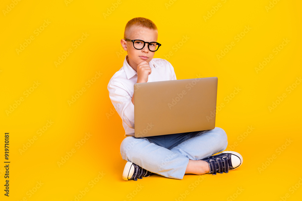 Photo of clever intelligent pensive boy wear white shirt sit floor isolated on yellow color background Photo of clever intelligent pensive boy wear white shirt sit floor isolated on yellow color background