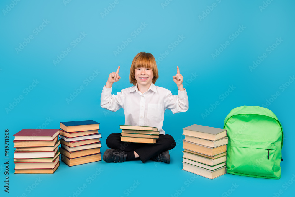Full body portrait of little schoolchild boy book direct fingers up empty space wear uniform isolated on blue color background Full body portrait of little schoolchild boy book direct fingers up empty space wear uniform isolated on blue color background