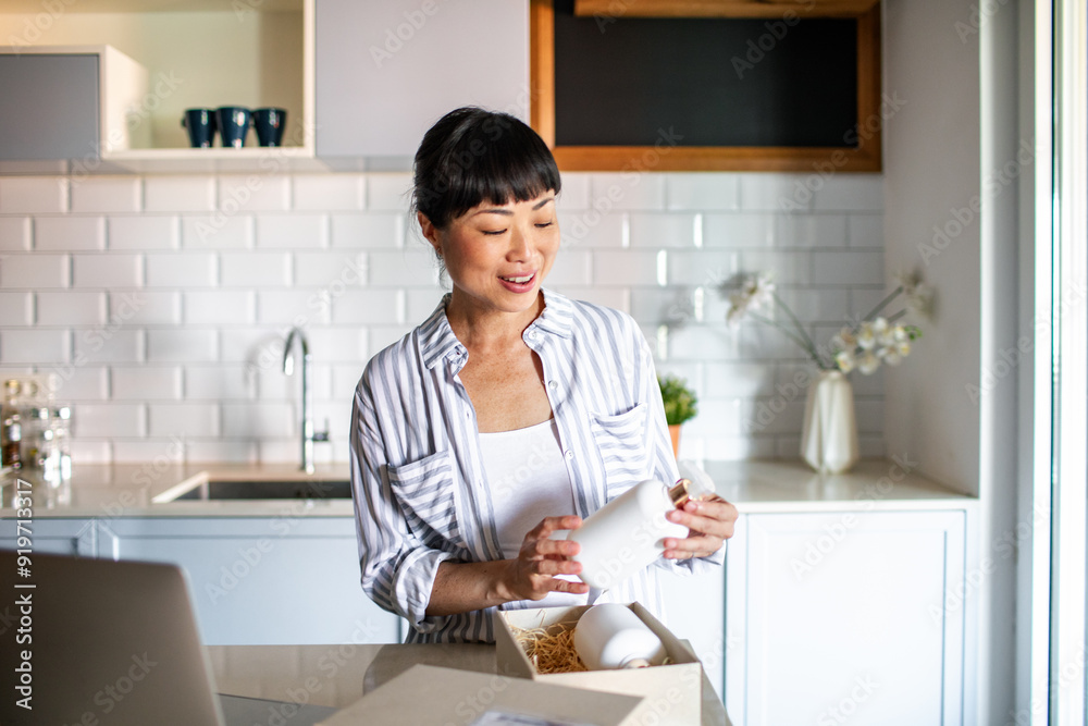 Happy Asian woman opening package in the kitchen Happy Asian woman opening package in the kitchen
