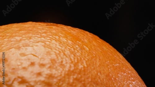 Macrography, the intricate texture of an orange against a striking black background steals the spotlight. Close-up shot captures the unique patterns and details of the orange's surface. Comestible.