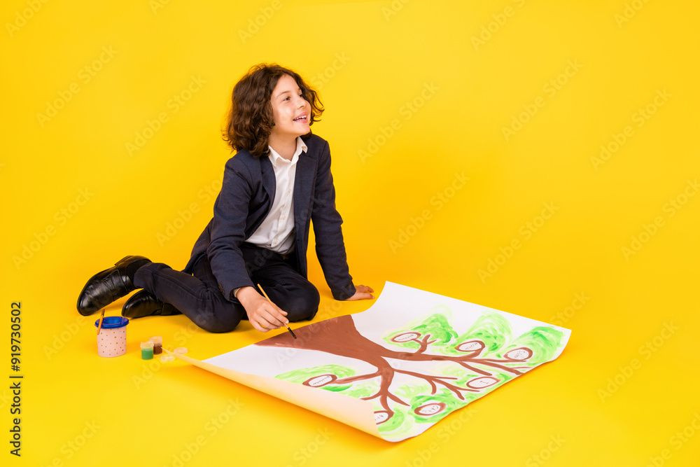 Full body photo of cute little schoolboy diligent sit floor draw family tree dressed stylish uniform isolated on yellow color background Full body photo of cute little schoolboy diligent sit floor draw family tree dressed stylish uniform isolated on yellow color background