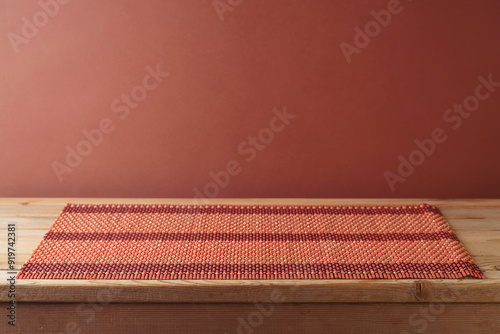 Empty wooden table with bamboo place mat over brown wall background.  Kitchen mock up for design and product display photo