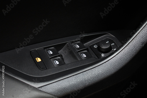 Car interior details of door handle with windows controls and adjustments. Car window controls and details. Modern car window control panel and door handle with power window control.