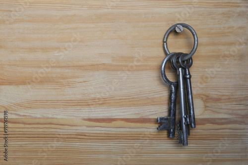 Antique keys on a metal ring hanging on a wooden wall