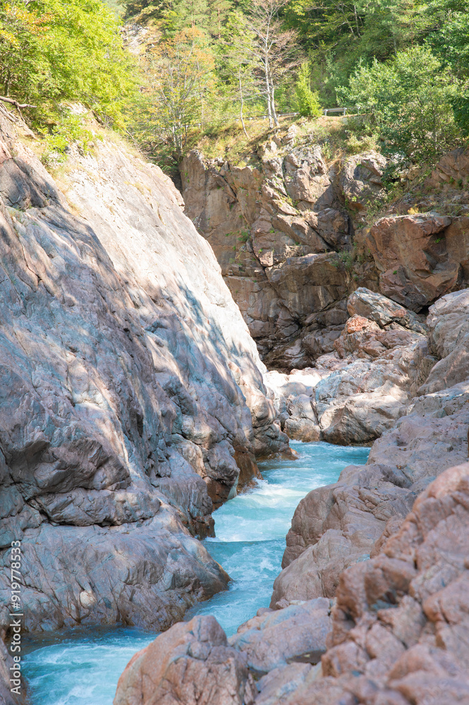 Naklejka premium A stormy mountain river flowing in a narrow rocky gorge