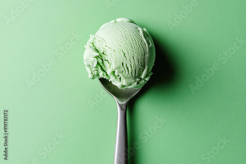 A top-down view of a mint green ice cream scoop on a mint green background.