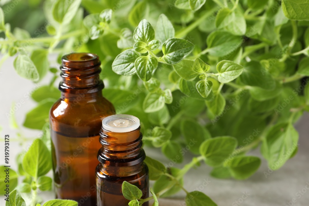 Essential oil in bottles and oregano twigs on table, closeup Essential oil in bottles and oregano twigs on table, closeup