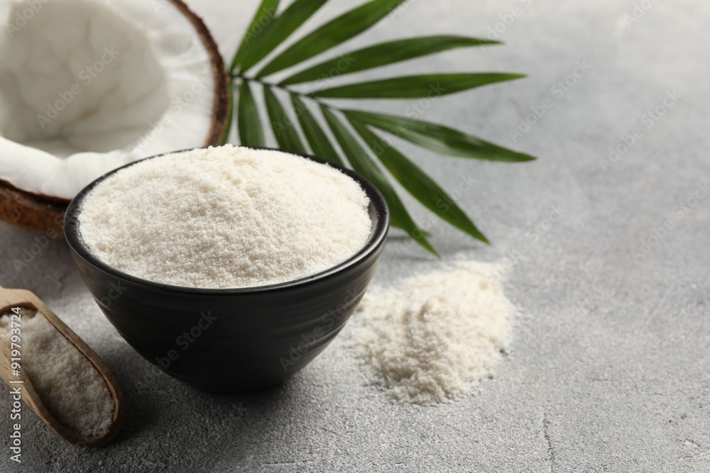 Coconut flour in bowl, scoop, fresh fruit and leaf on light grey table. Space for text Coconut flour in bowl, scoop, fresh fruit and leaf on light grey table. Space for text