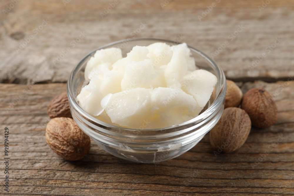 Shea butter in bowl and nuts on wooden table, closeup Shea butter in bowl and nuts on wooden table, closeup