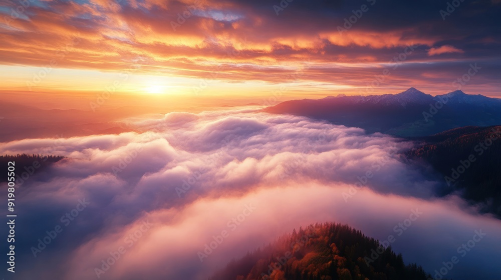 Naklejka premium Majestic Sunrise Above the Clouds in Mountain Range - Breathtaking aerial view of a sunrise casting vibrant hues over a sea of clouds and distant mountain peaks. Perfect for nature lovers.