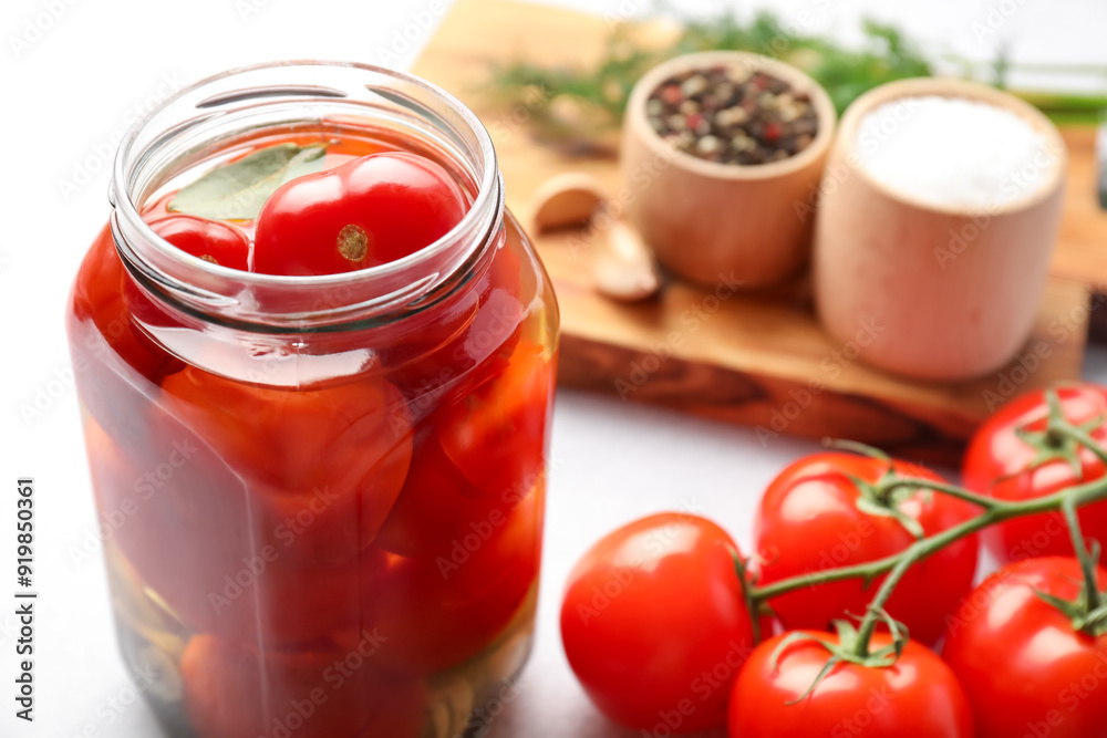 Tasty pickled tomatoes in jar, fresh vegetables and spices on white table, closeup Tasty pickled tomatoes in jar, fresh vegetables and spices on white table, closeup