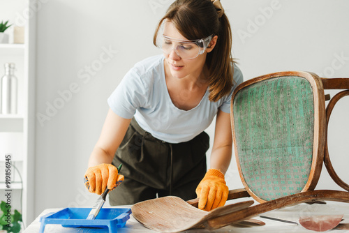 Fotografie Woman restoring old chair using paint and varnish remover