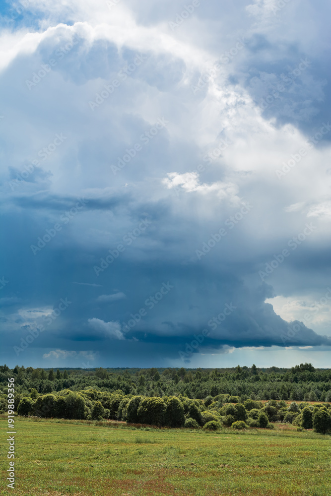 Blue thunder storm sky with rain over green forest and field. Summer landscape on cloudy rainy day Blue thunder storm sky with rain over green forest and field. Summer landscape on cloudy rainy day