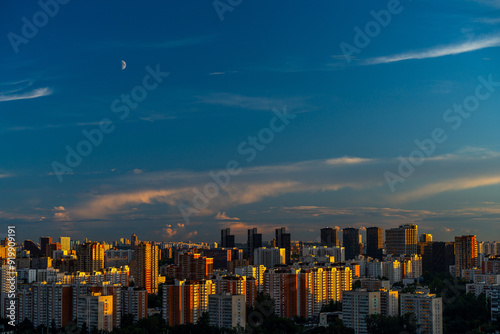 A beautiful sunset over a big city, high-rise residential buildings and skyscrapers illuminated by the setting sun against the blue sky. View from above. Moscow, Khovrino district. photo