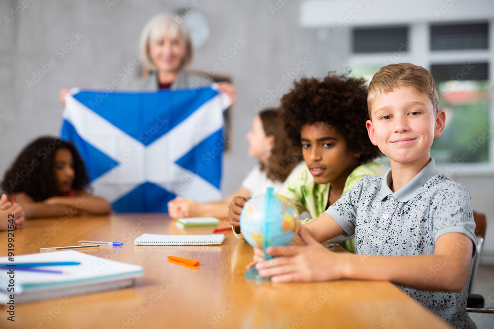 Fototapeta premium Ten-year-old schoolboy is studying the history of Scotland in lesson and is looking for her on the globe