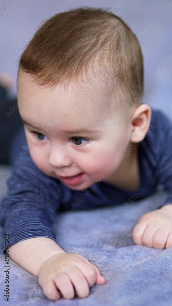 Nice Caucasian baby boy lying on his tummy on big bed. Mom's hand reaches the son and he responds with a cute smile. Grey backdrop in blur. Vertical video Nice Caucasian baby boy lying on his tummy on big bed. Mom's hand reaches the son and he responds with a cute smile. Grey backdrop in blur. Vertical video
