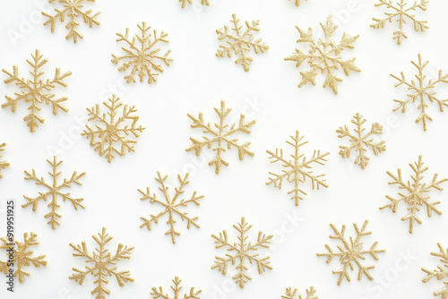 Golden snowflakes arranged on a white background, creating an elegant holiday pattern with ample copy space for festive designs.