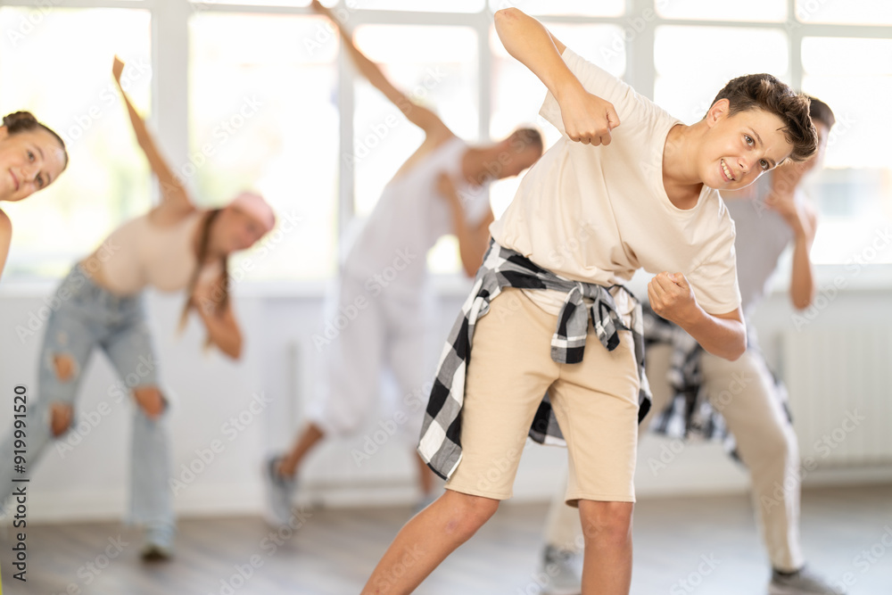 Obraz premium Teenage boy rehearsing hip hop dance in group in dance studio