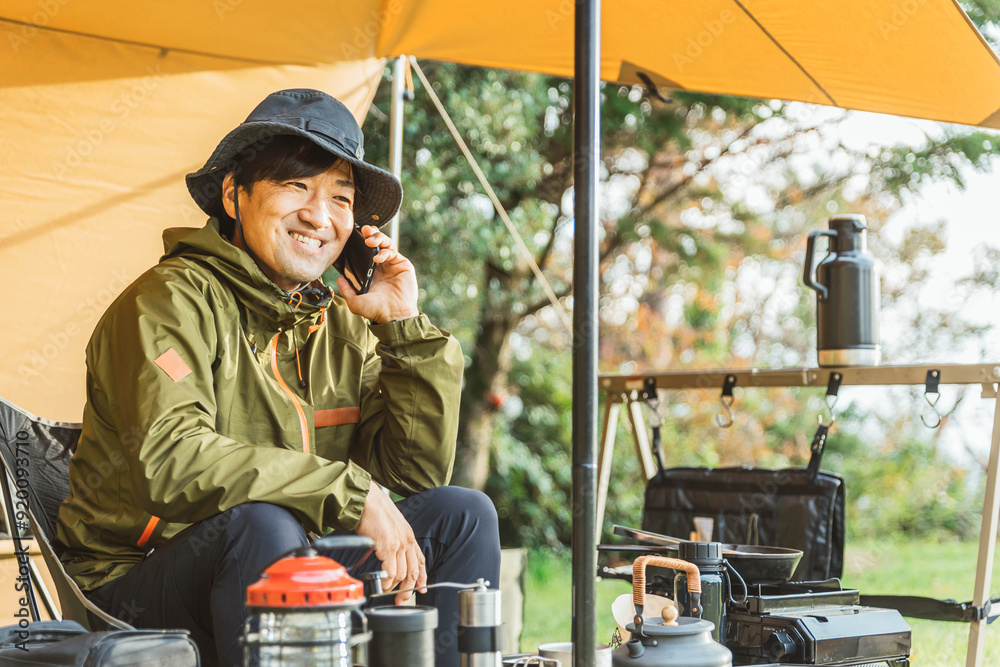 Φωτογραφία キャンプ場でスマホを使う中年男性キャンパー（キャンプ場・通話・話す）