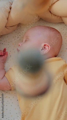 Newborn baby is sleeping in cosy cradle with spinning crib mobile. Handheld high angle shoot with shallow depth of field.