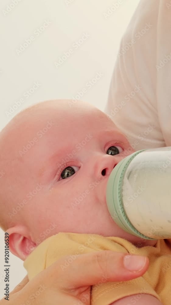 Mother holding newborn baby on hands and feeding from milk bottle. Motherhood. Little child eating milk at home. Healthy infant nutrition. Mother holding newborn baby on hands and feeding from milk bottle. Motherhood. Little child eating milk at home. Healthy infant nutrition.