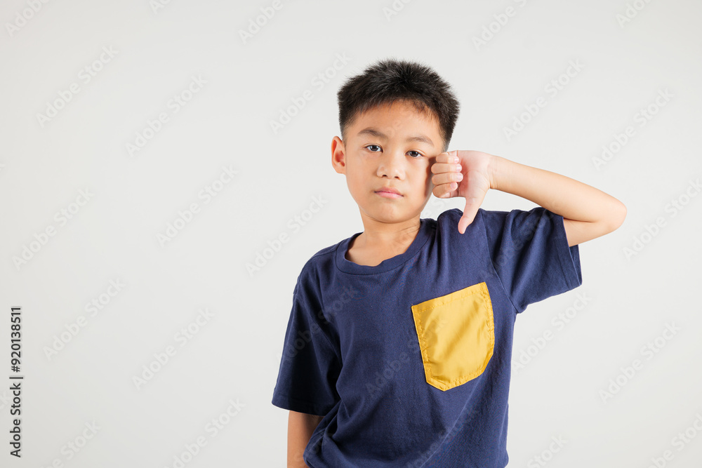 Portrait disheartened Asian young kid boy displaying a thumbs down gesture, symbolizing dislike. Studio shot isolated on white with ample copy space, primary child portraying negative and sad look Portrait disheartened Asian young kid boy displaying a thumbs down gesture, symbolizing dislike. Studio shot isolated on white with ample copy space, primary child portraying negative and sad look