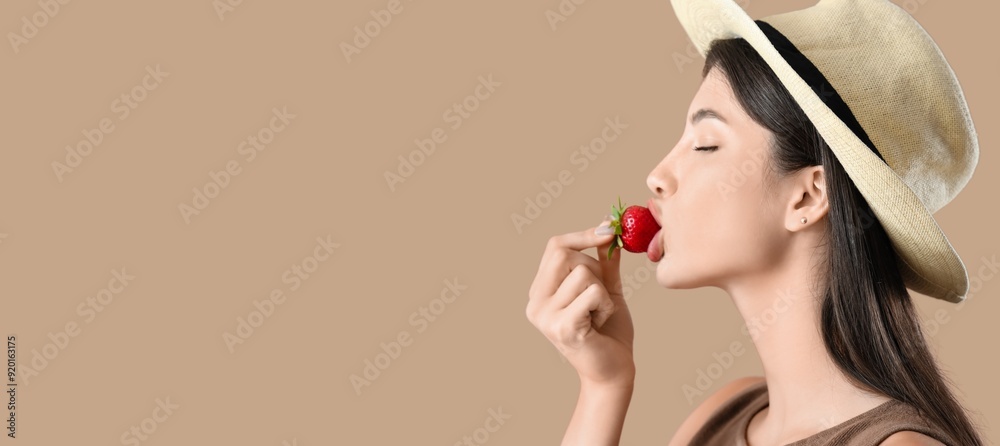Young woman eating fresh strawberry on brown background with space for text Young woman eating fresh strawberry on brown background with space for text