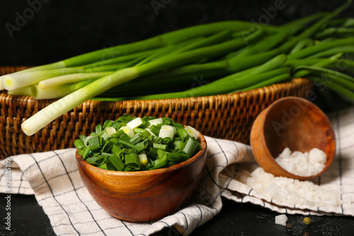 Bowl with fresh cut green onion on dark background