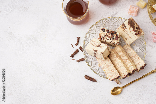 Pieces of tasty marble halva and glass with Turkish tea on white background photo