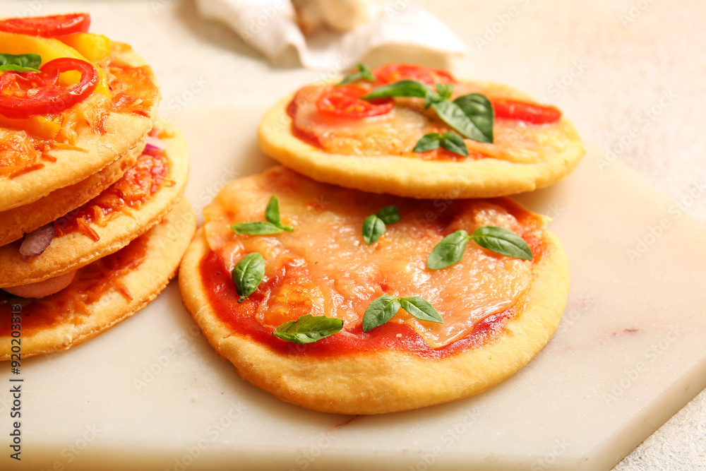 Board with different tasty mini pizzas on white background Board with different tasty mini pizzas on white background