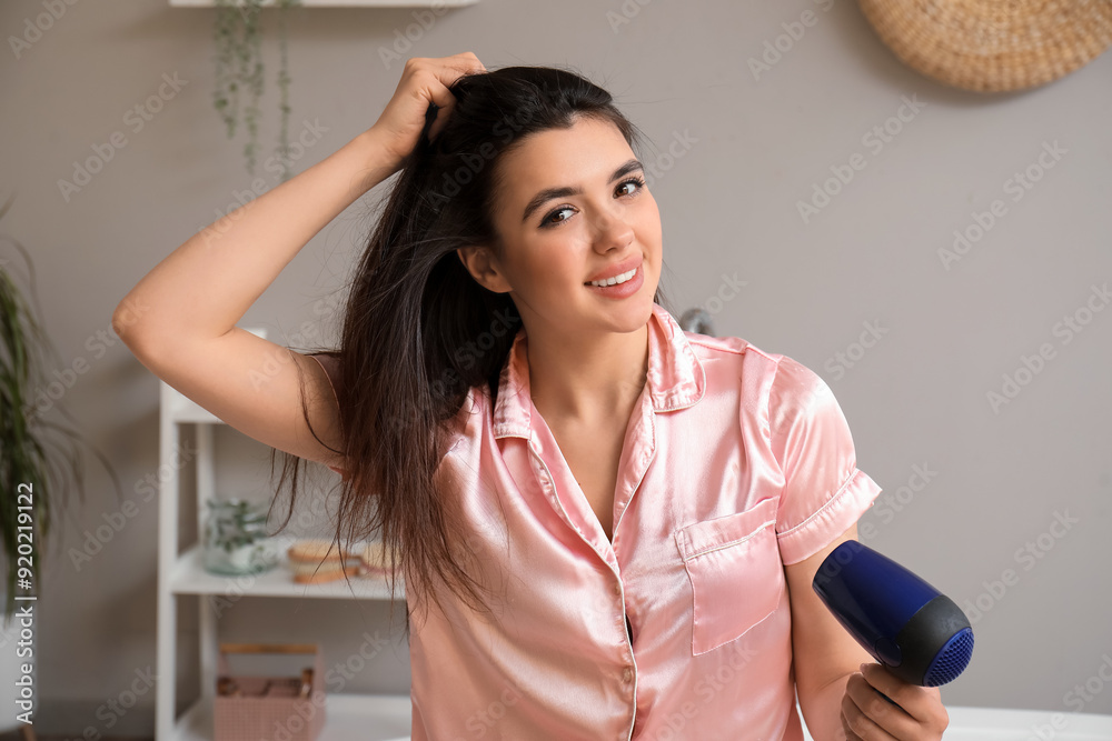 Pretty young woman with hair dryer in bathroom Pretty young woman with hair dryer in bathroom