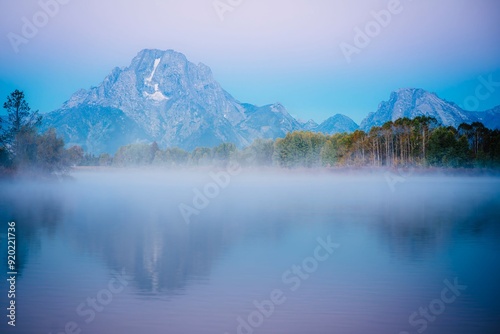 Stunning landscape of a misty lake with mountains in the background during dawn