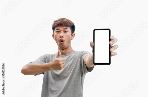 Asian man in gray t-shirt makes wow face and gives thumbs up on mobile phone with blank white smartphone screen isolated on gray background. People recommending new applications or mobile websites