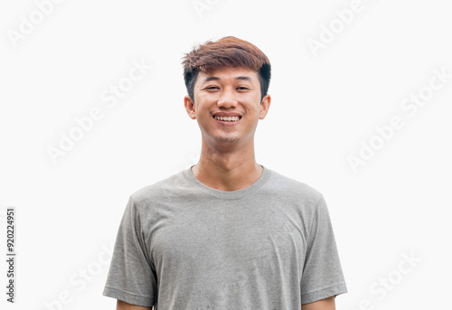 Young man in gray t-shirt smiling happily isolated on gray background