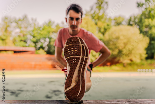 Experienced runner stretching his legs before starting his training session photo