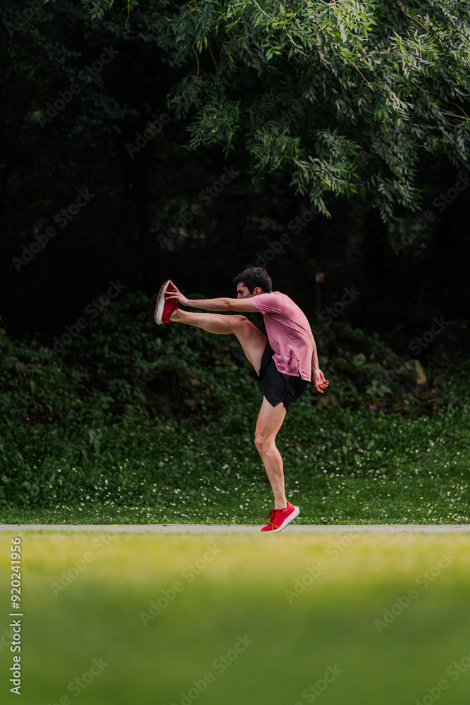 Young man lifting his legs to warm up before going for a run. Vertical Young man lifting his legs to warm up before going for a run. Vertical