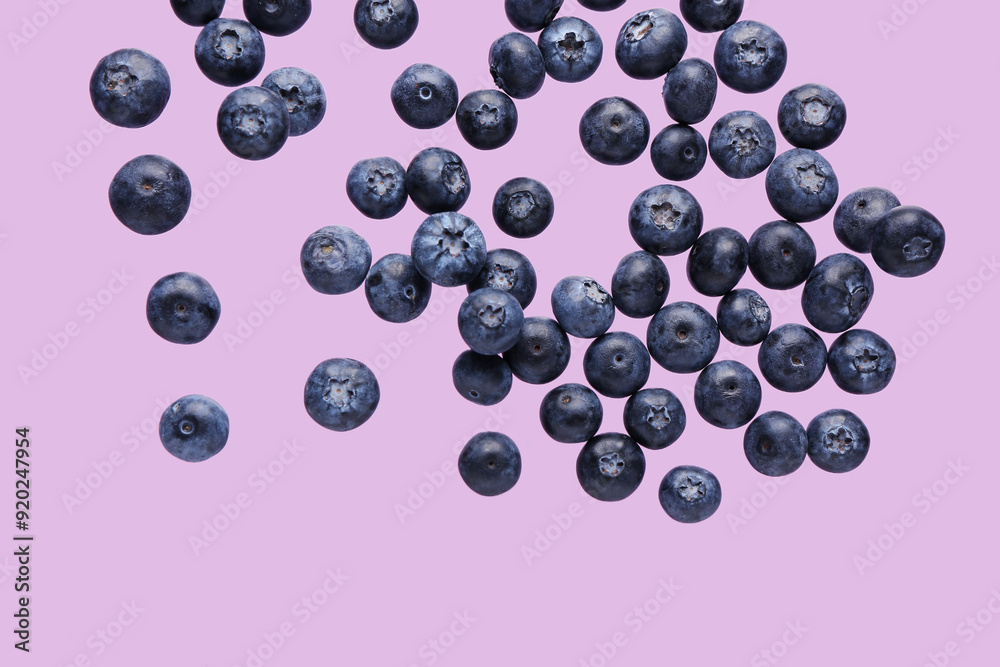 Flying sweet fresh blueberries on lilac background Flying sweet fresh blueberries on lilac background