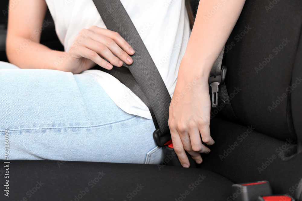 Woman fastening seat belt in car, closeup Woman fastening seat belt in car, closeup