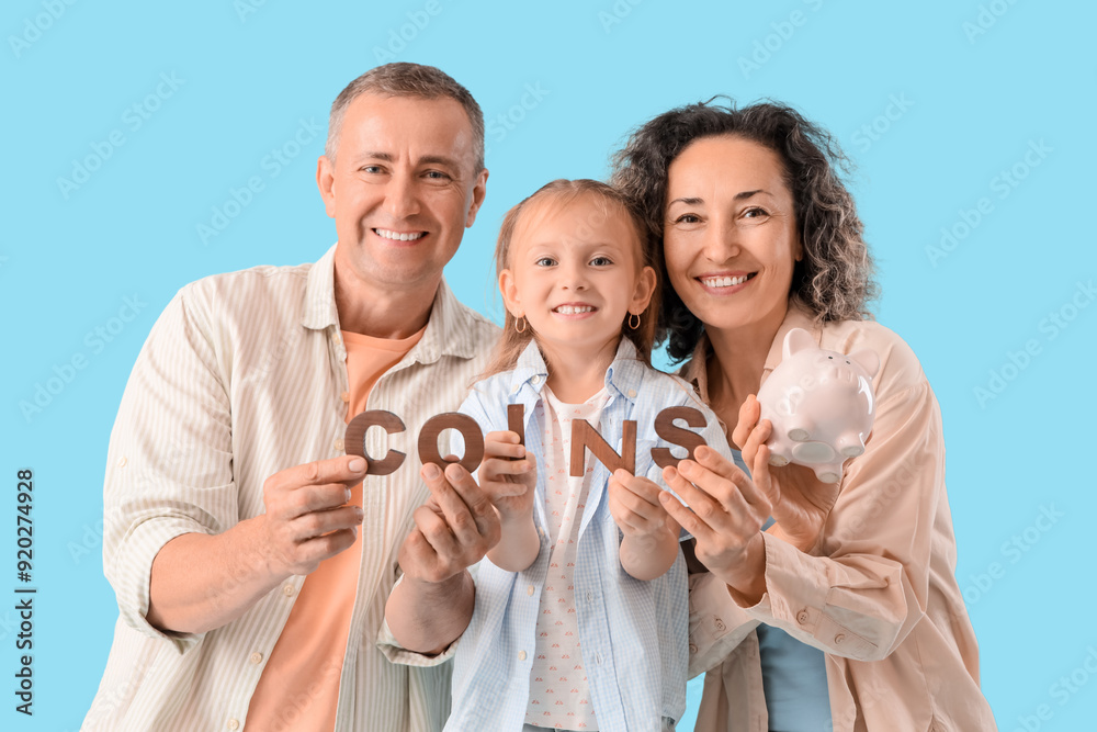 Fototapeta premium Happy family with piggy bank and word COINS on blue background