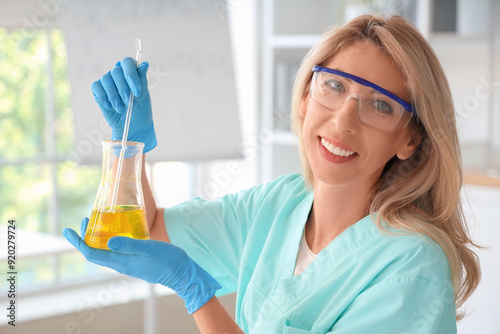 Happy female scientist with flask of sunflower sample working in laboratory