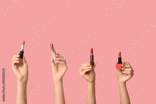 Female hands with many lipsticks on pink background