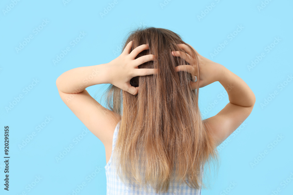 Little girl with pediculosis scratching her head on blue background, back view Little girl with pediculosis scratching her head on blue background, back view