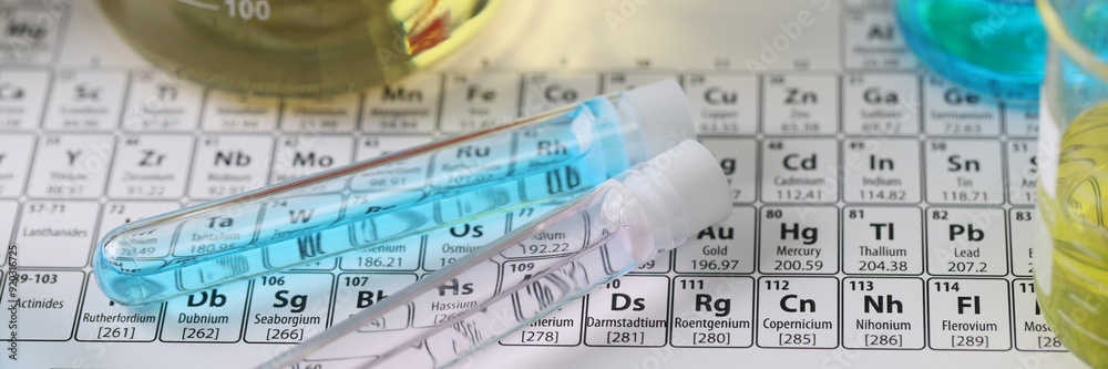 Research laboratory glassware with liquids on periodic table of chemical elements Research laboratory glassware with liquids on periodic table of chemical elements