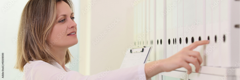 Female doctor pick up folder from row in medical clinic Female doctor pick up folder from row in medical clinic