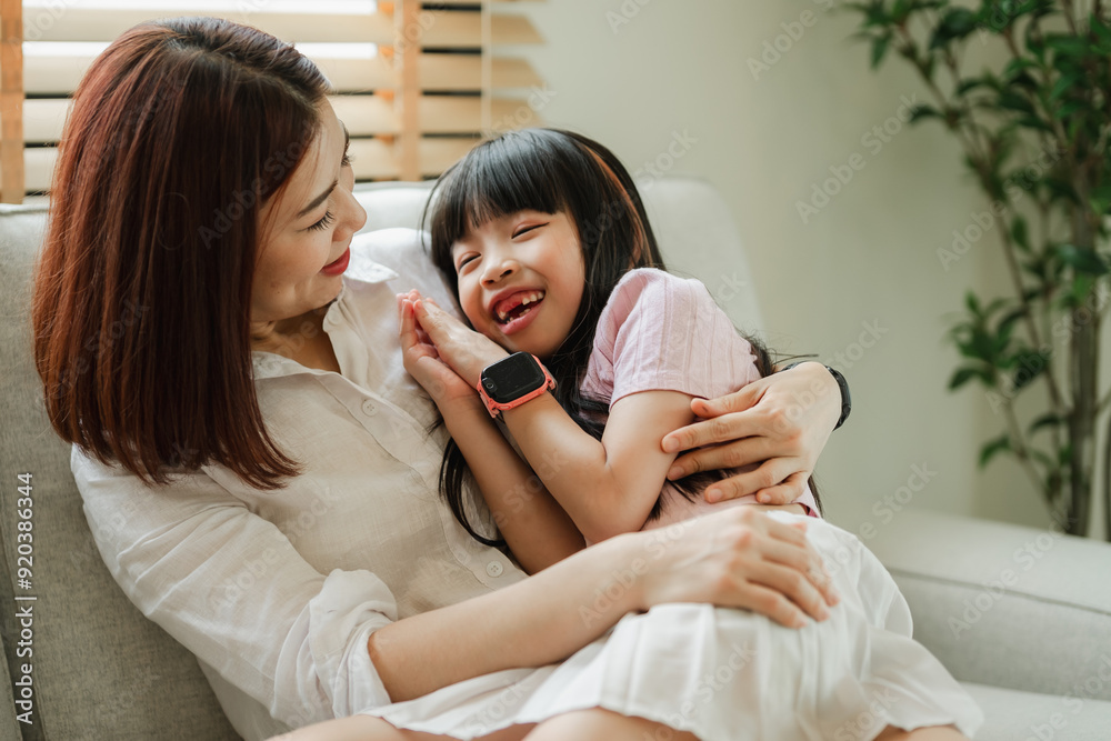 A woman and a child are sitting on a couch, the woman is holding the child