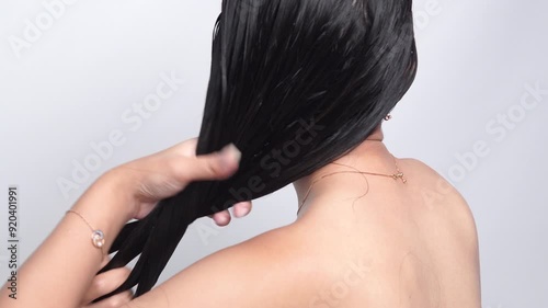 Beautiful young Asian woman with long hair is getting her hair washed using conditioner.
